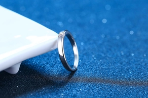 Macro shot of S925 sterling silver ring with princess cut moissanite on a blue background