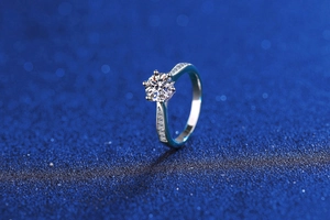 Macro view of a 2-carat moissanite ring with six-prong setting on a shimmering blue background