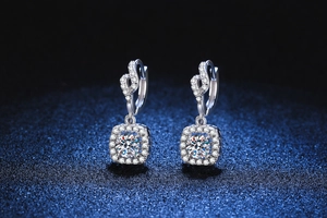 Detail of s925 silver moissanite drop earrings with halo setting on dark blue background