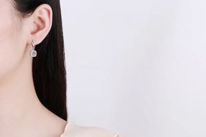 Close-up of S925 silver moissanite halo earrings with sparkling stones on a model