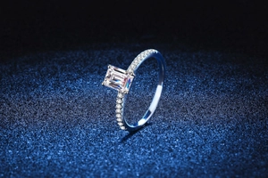 Macro view of emerald-cut moissanite stone with pave set diamonds on s925 silver band
