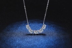 Gros plan du collier en argent S925 avec cinq pierres moissanite étincelantes sous lumière bleue