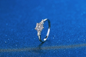 Macro side view of heart-cut moissanite ring with baguette side stones on blue background