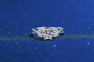 Macro shot of 1ct moissanite ring with leaf-shaped side stones on a starry blue base
