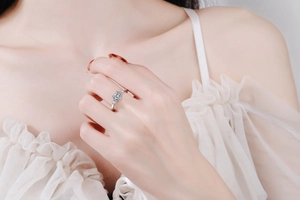 Macro shot of a sparkling heart-shaped Moissanite ring on a finger with white lace clothing