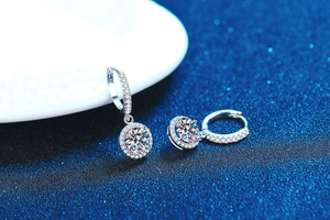 Macro view of 1ct moissanite earrings with S925 silver hoop on dark blue background