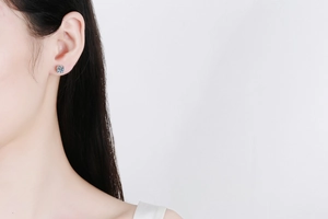 Close-up of s925 silver four-prong moissanite stud earring worn on model's ear