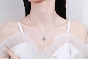 Modèle portant un collier avec pendentif halo carré et une grande moissanite ronde en argent
