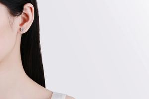 Close-up of heart-shaped moissanite stud earring in silver on a model's ear