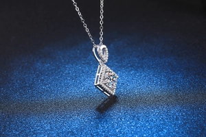 Macro view of geometric silver pendant featuring a large Moissanite and micro-pave setting