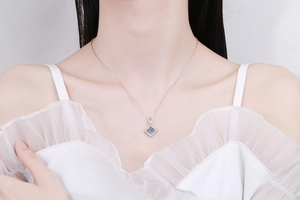 Close-up of a s925 silver necklace featuring a square blue moissanite pendant on a model