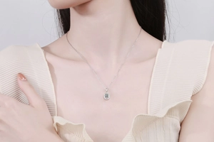 Detail of elegant silver moissanite necklace with oval pendant worn by a model