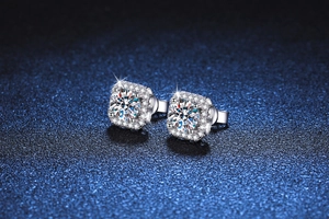 Macro shot of square halo moissanite earrings on a textured dark blue surface
