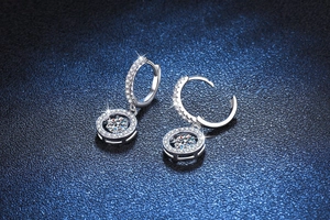 Close-up of S925 silver halo earrings with sparkling stones on dark textured background