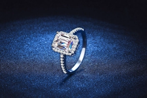 Dettaglio anello in moissanite taglio smeraldo con incastonatura halo su blu