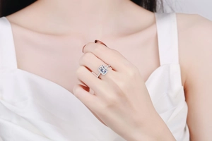 Nahaufnahme eines Moissanit-Rings mit Smaragdschliff und Diamant-Halo an einem Finger