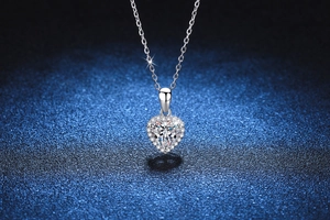 Macro detail of heart-shaped moissanite pendant with halo setting on a blue background