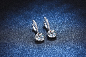Detailed macro view of S925 sterling silver moissanite drop earrings on dark blue background