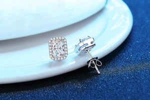 Close-up of radiant cut moissanite earrings with halo diamonds and silver studs