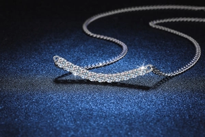 Gros plan du collier Smile en argent S925 serti de moissanites sur un fond bleu foncé