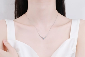 Detail view of a V-shaped sterling silver necklace with blue pear-cut moissanite pendant
