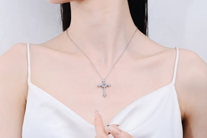 Close-up of a s925 sterling silver cross necklace with pavé moissanite stones on a model
