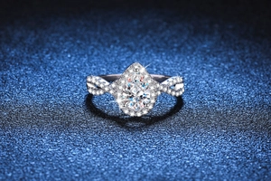 Macro shot of a 1-carat pear cut moissanite ring with halo and twisted pave band