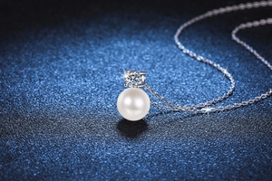 Close-up of S925 silver necklace featuring a moissanite stone and round pearl pendant