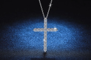 Macro shot of 1.6 carat Moissanite cross pendant with round cut diamonds on blue texture