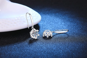 Macro view of snowflake moissanite earrings with heart shaped six prong silver setting