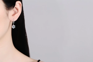 Close-up of S925 silver snowflake earrings with 1 carat D color moissanite on ear