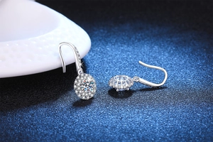 Macro shot of silver drop earrings with brilliant round moissanite in halo setting
