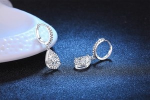 Close-up of pear-cut moissanite drop earrings in S925 silver with pavé diamond setting