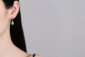 Detailed close-up of pear-cut moissanite drop earrings in S925 sterling silver on a model