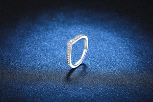 Macro shot of V-shaped S925 silver ring with pavé moissanite on a navy background