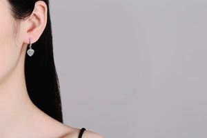 Close-up of heart-shaped moissanite earrings in S925 sterling silver worn by a model