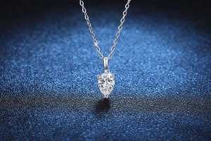 Macro shot of 1 carat pear-cut moissanite pendant with silver chain on starry background
