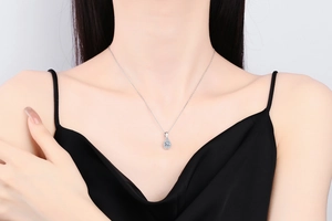 Gros plan d'un pendentif goutte en moissanite sur une chaîne en argent porté par un mannequin