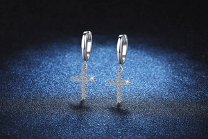 Macro detail of S925 silver hoop earrings featuring full moissanite paved cross pendants