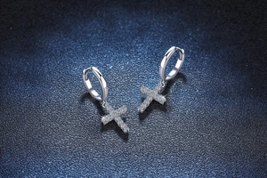 Close-up of S925 silver cross drop earrings with pavé moissanite on a navy background