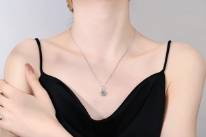 Detailed view of a classic moissanite pendant necklace worn on a woman's collarbone