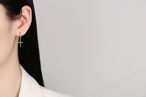 Close-up of S925 silver cross drop earring with micro-pave moissanite on female model