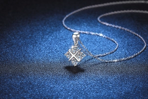 Détail du collier en argent s925 avec pendentif carré en X et moissanite sur fond bleu