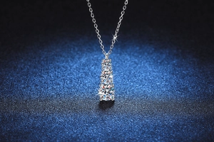 Gros plan du pendentif en moissanite triple avec chaîne en argent sur fond bleu foncé