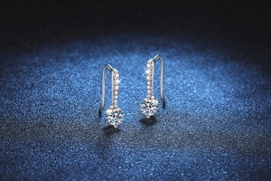 Detail of s925 silver moissanite drop earrings with teardrop hook on blue texture