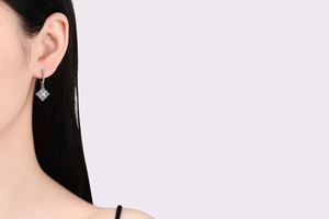 Detail of silver drop earrings with blue stones worn on a model against a soft background