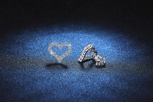 Macro view of heart-shaped S925 silver earrings with full pavé moissanite and butterfly back