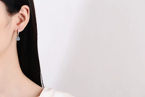 Close-up of a classic six-prong moissanite drop earring worn on a model's ear