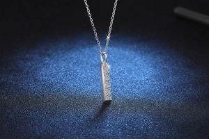 Macro shot of silver vertical bar pendant with moissanite diamonds on a thin chain