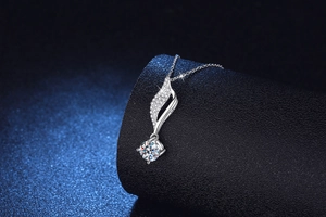 Détail macro du pendentif feuille en argent avec moissanite étincelante sur support noir